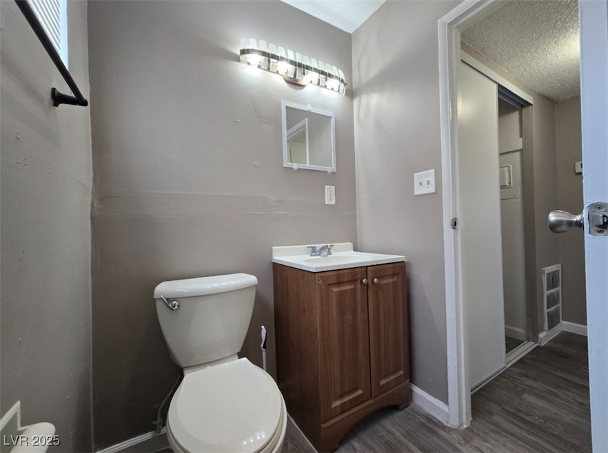Half bathroom with wood finished floors, toilet, b