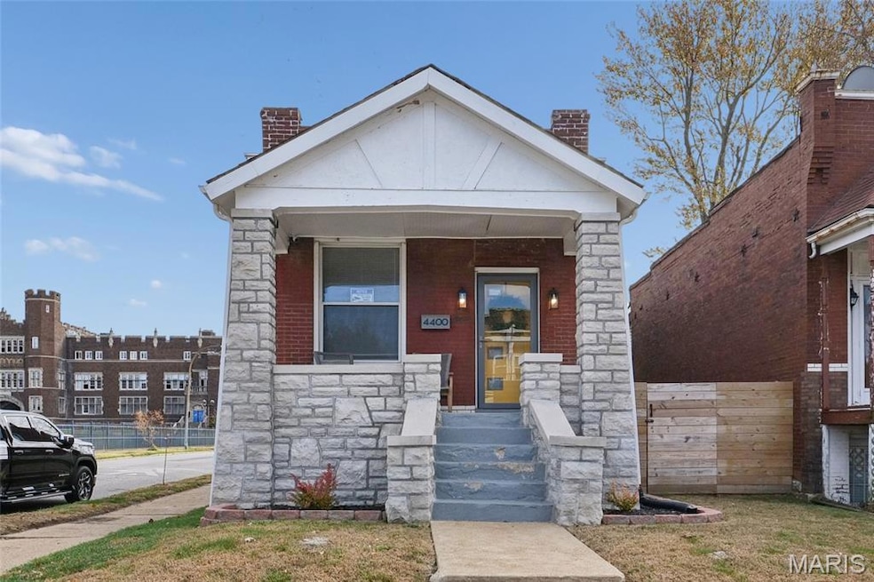 View of front of house with a chimney, stone siding, and a porch