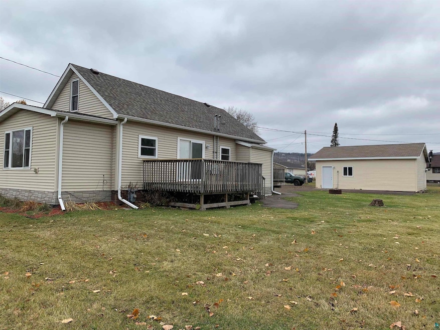 Back of property featuring a wooden deck and a yar