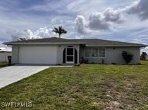 Single story home with a garage and a front lawn