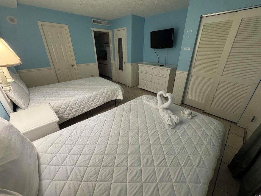 Bedroom with a wainscoted wall, a closet, light ti