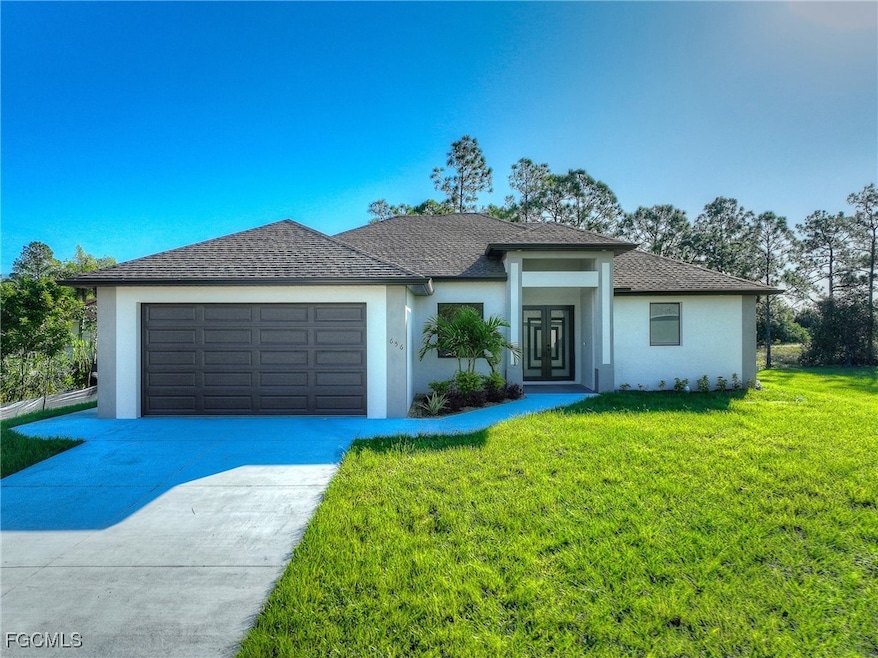 Prairie-style house featuring a front yard, stucco siding, driveway, and a garage