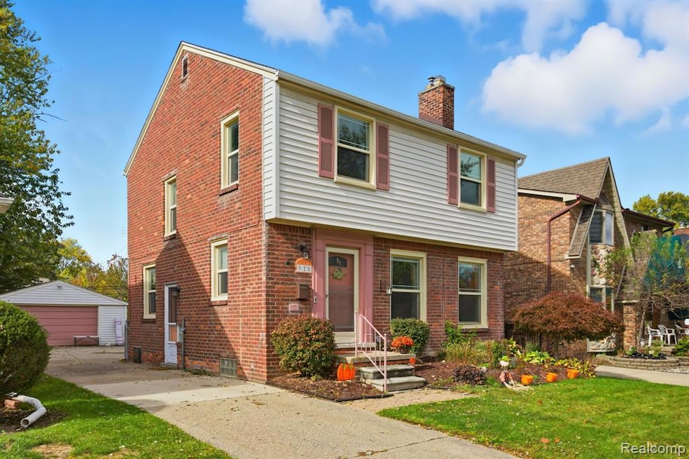 View of front of house featuring an outbuilding, a chimney, a front yard, brick siding, and a detached garage