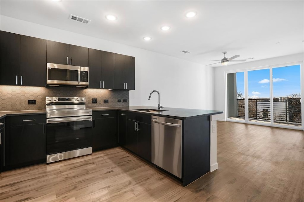 Kitchen with tasteful backsplash, stainless steel appliances, a peninsula, dark countertops, and recessed lighting