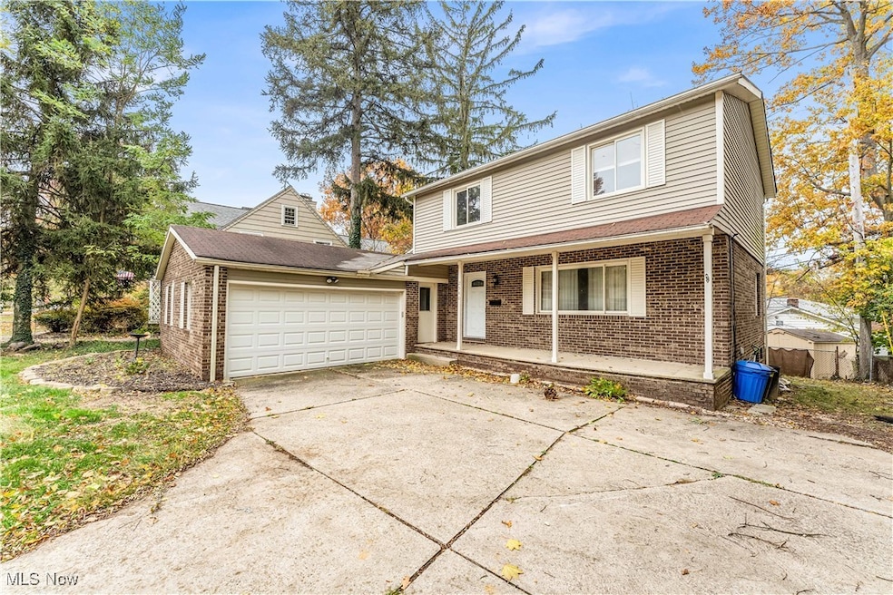 Traditional home featuring concrete driveway, covered porch, brick siding, and a garage