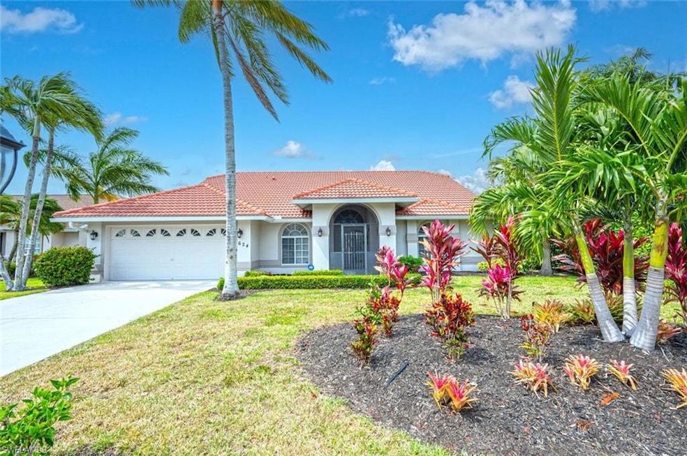 Mediterranean / spanish home with a tiled roof, an attached garage, stucco siding, concrete driveway, and a front lawn