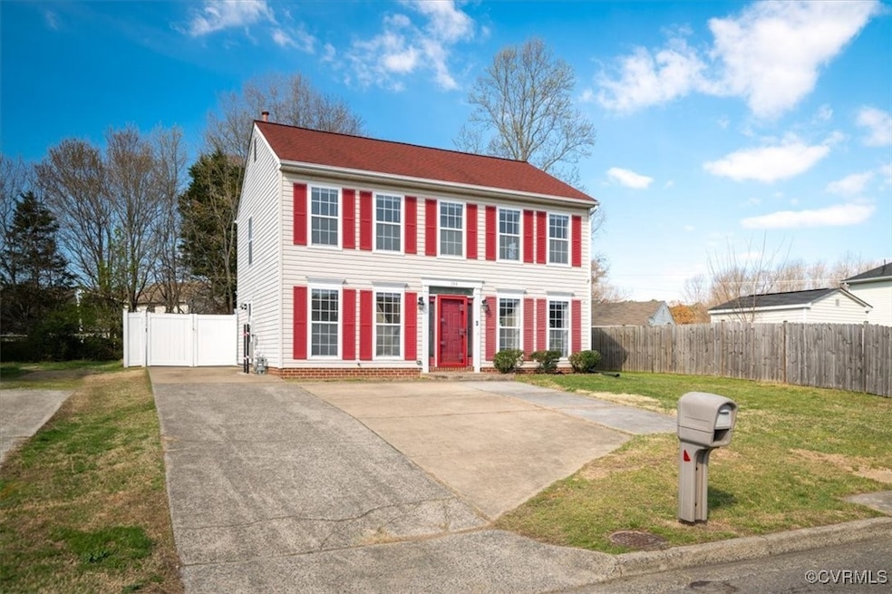 Colonial house with a gate, fence, a front lawn, a