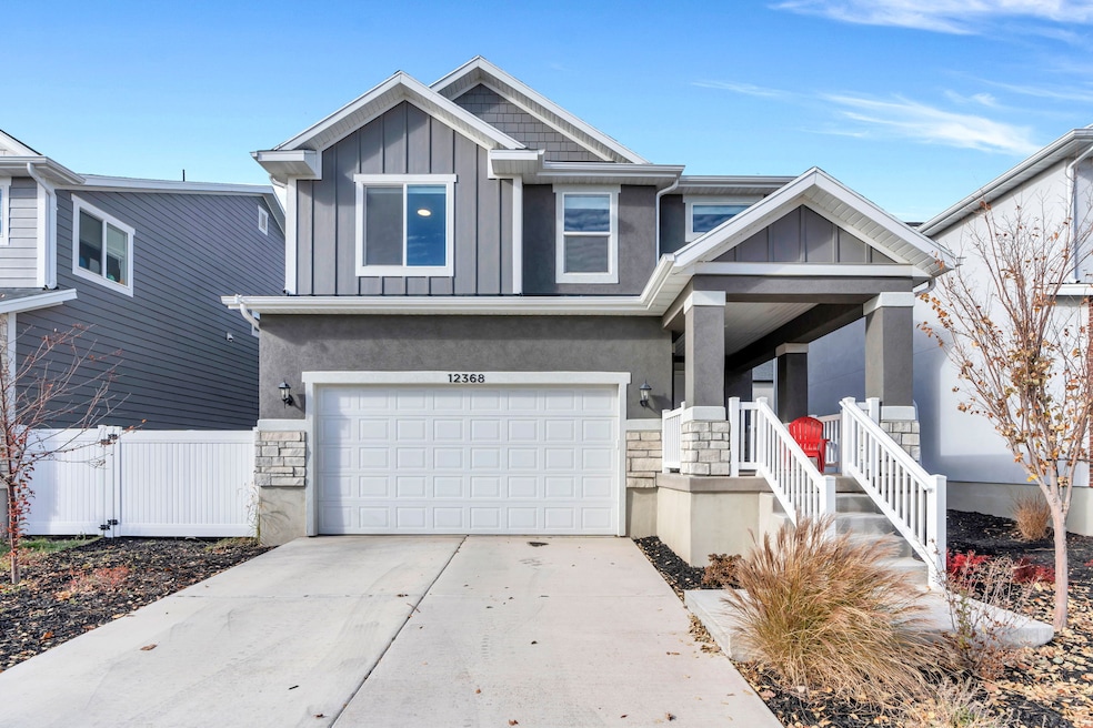 View of front of home with board and batten siding, stone siding, covered porch, concrete driveway, and a garage
