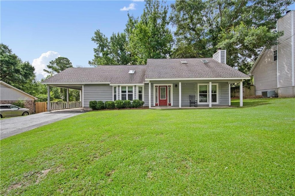 View of front of home featuring a porch, a chimney, driveway, an attached carport, and roof with shingles