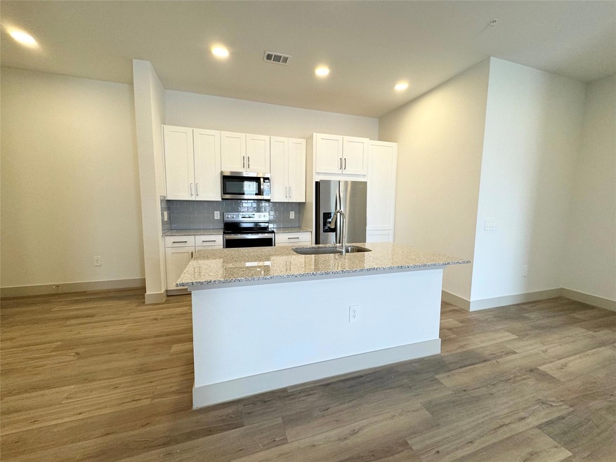 Kitchen with white cabinets, appliances with stain