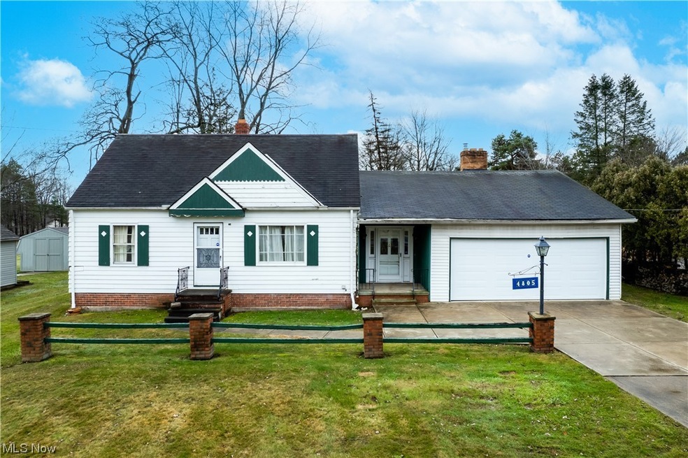 View of front of home featuring a storage unit, a garage, and a front yard