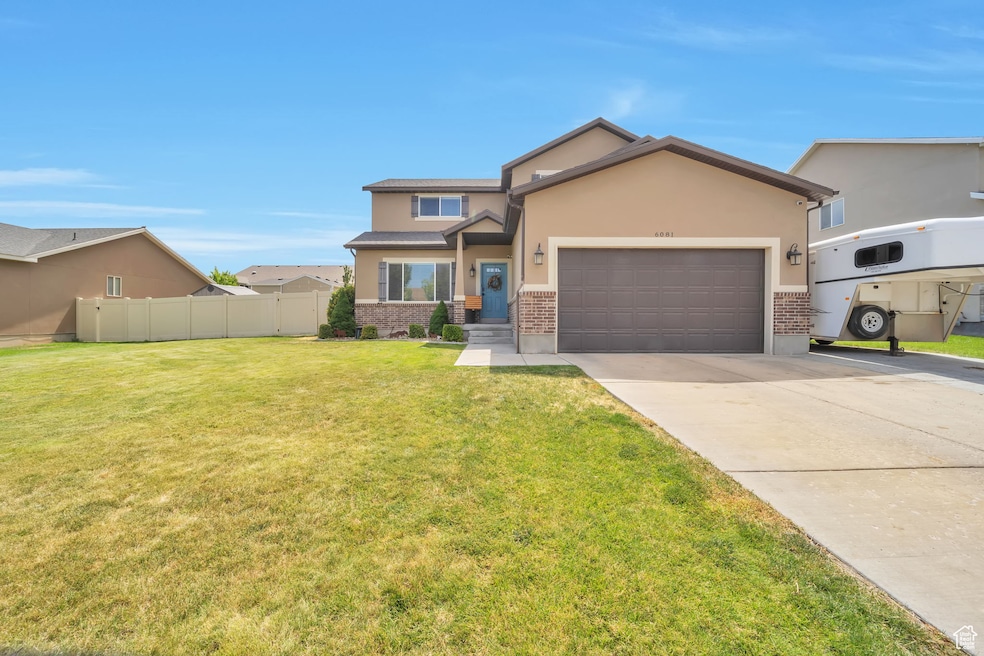 View of front of property with a garage, brick siding, driveway, and stucco siding