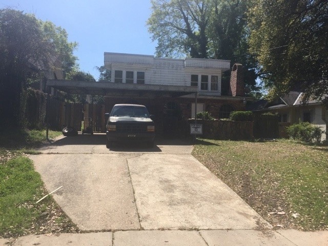 View of front of property with concrete driveway, a front lawn, and an attached carport