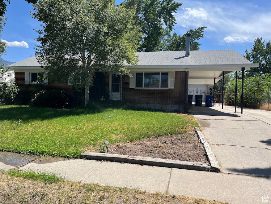 Single story home with brick siding, concrete driveway, and a carport
