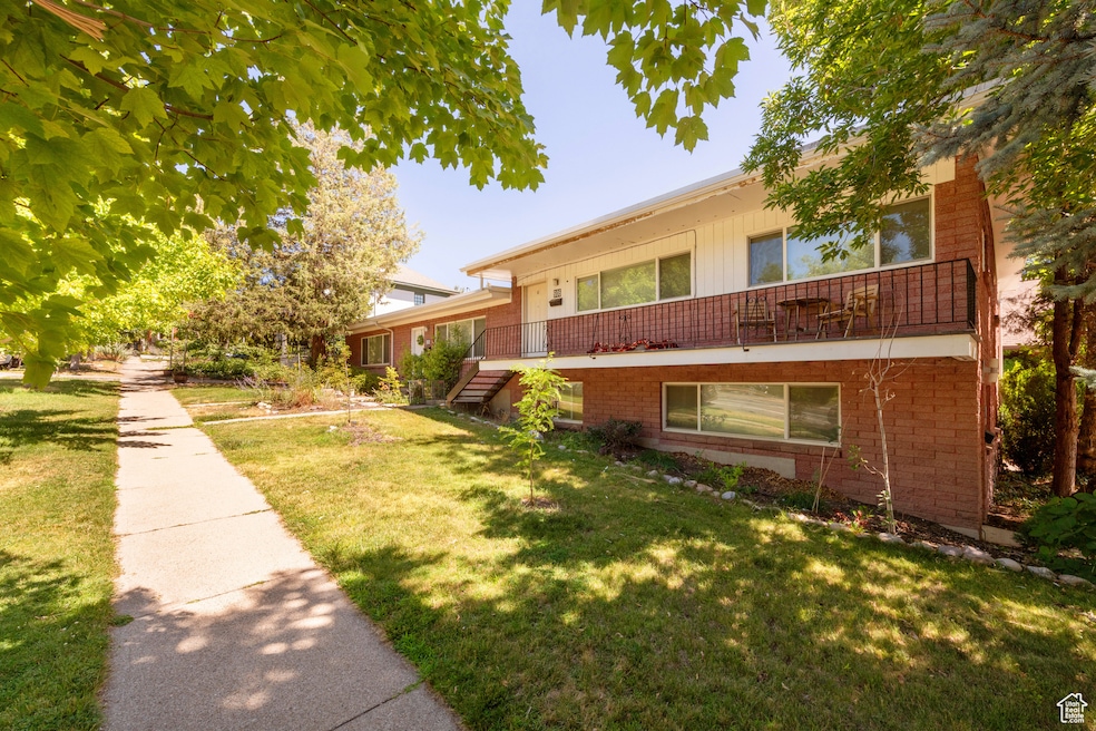 View of front facade with brick siding, a front yard, and a balcony