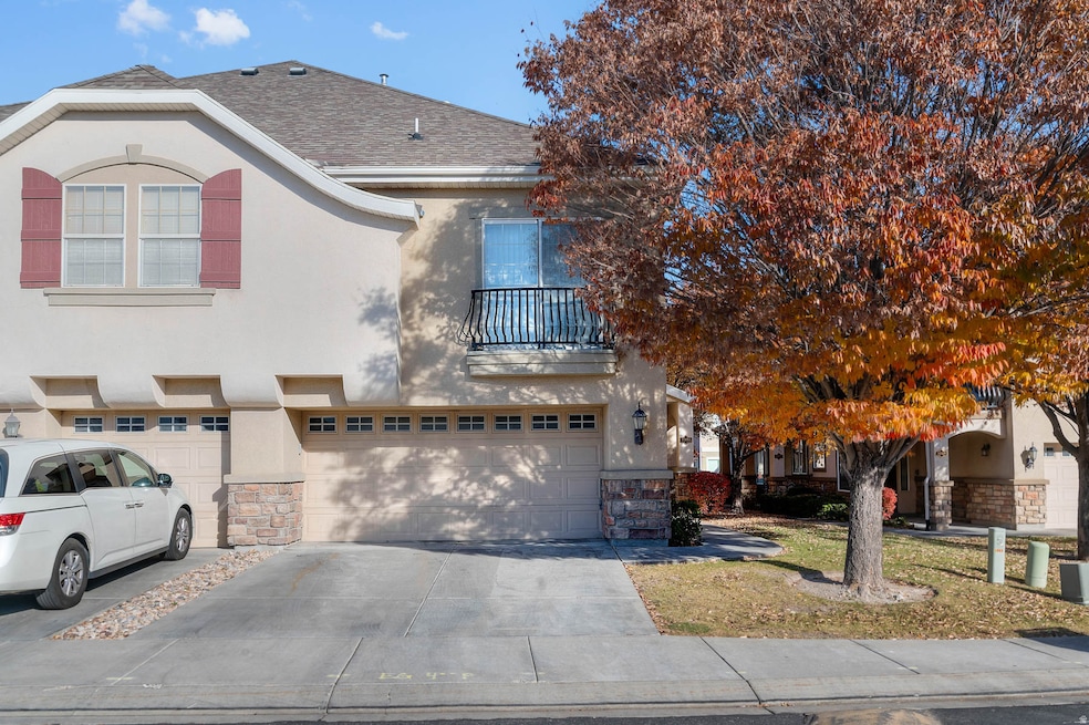View of front of house featuring a balcony, stucco siding, driveway, and a garage