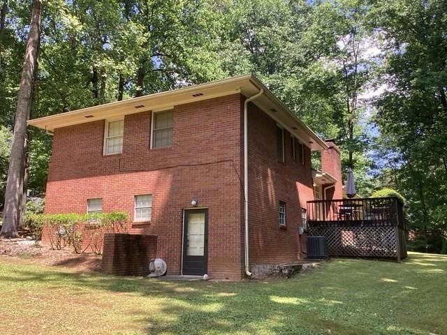 Rear view of house with brick siding, a yard, a wooden deck, and cooling unit