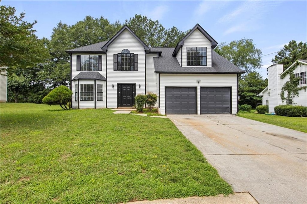 View of front of home featuring a front lawn, driveway, a garage, and a shingled roof