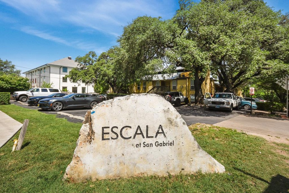 Community sign with a lawn and uncovered parking