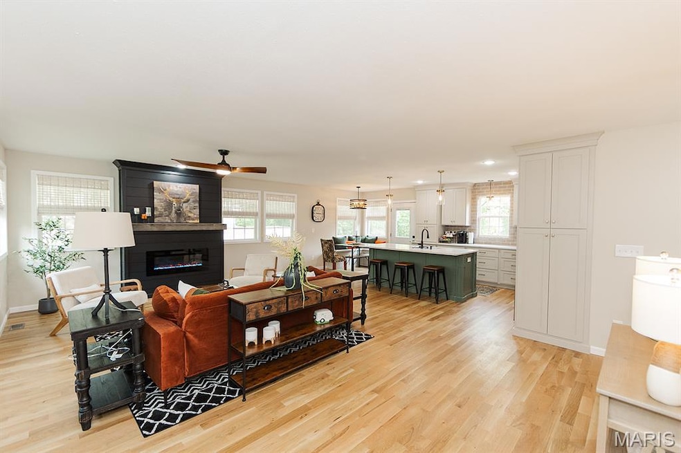 Living room featuring light wood finished floors, a ceiling fan, and a large fireplace
