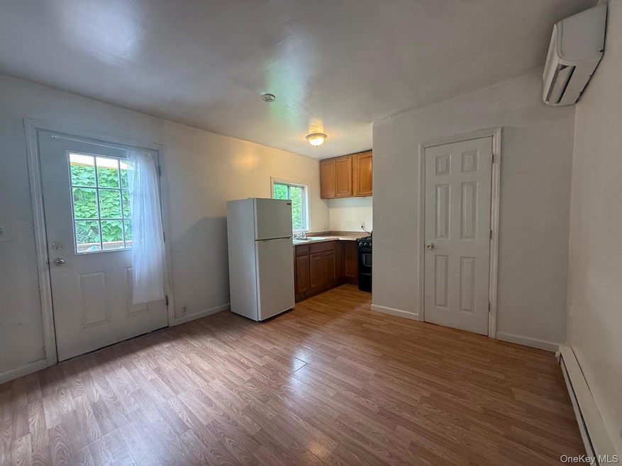 Kitchen featuring a baseboard heating unit, freestanding refrigerator, light countertops, light wood-style floors, and plenty of natural light