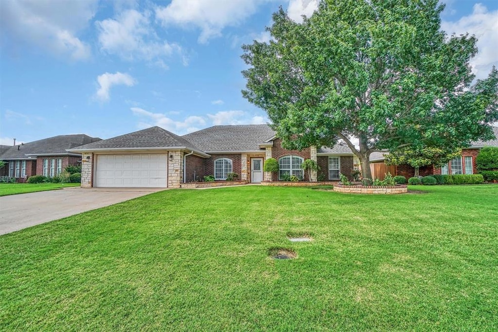 View of front of property featuring a garage, driveway, a front yard, brick siding, and roof with shingles