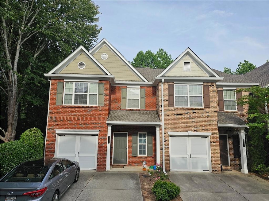 View of front facade with driveway, a garage, and brick siding