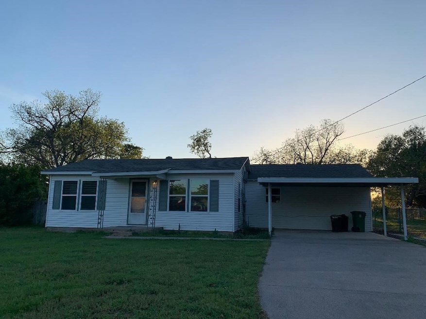 Single story home featuring a carport, a front lawn, and driveway