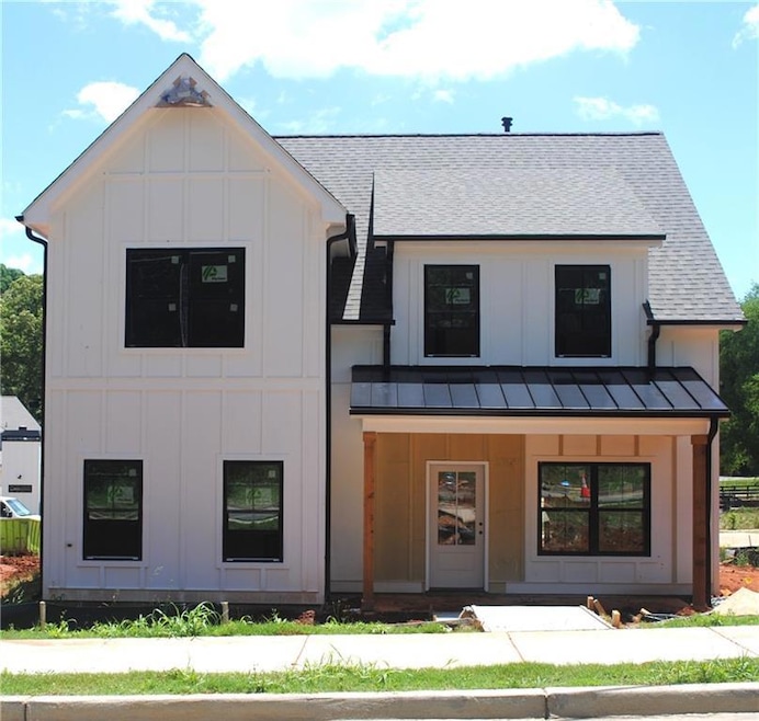 Modern farmhouse featuring board and batten siding, a standing seam roof, a shingled roof, and covered porch