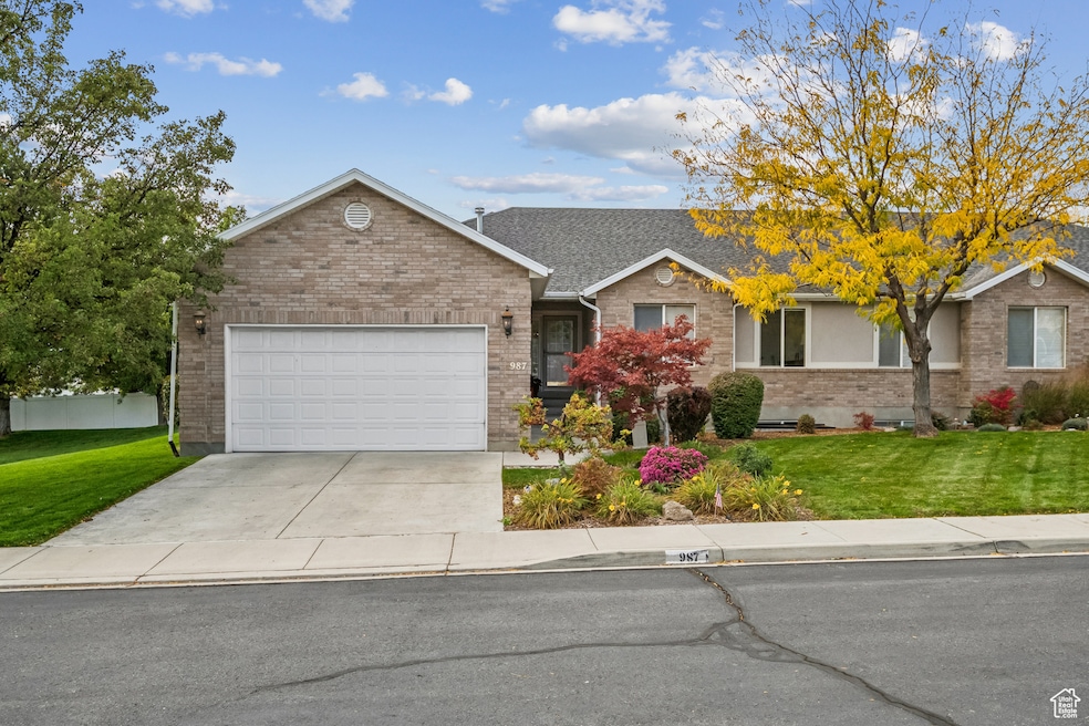 Ranch-style home with a front lawn, driveway, a garage, and brick siding