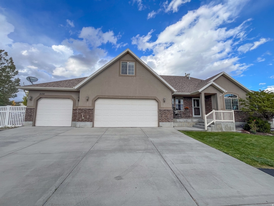 Ranch-style home with stucco siding, driveway, a garage, and brick siding
