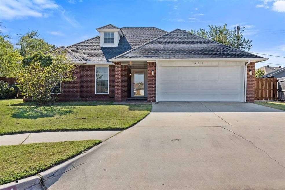 View of front facade featuring concrete driveway, a shingled roof, brick siding, and an attached garage