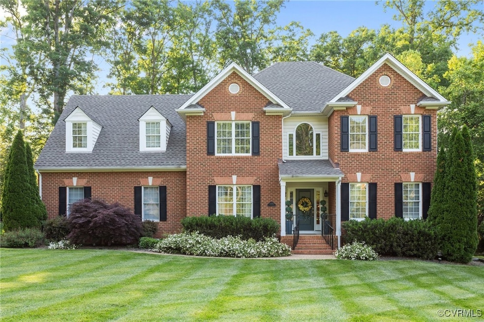 Georgian-style home with a front yard, a shingled