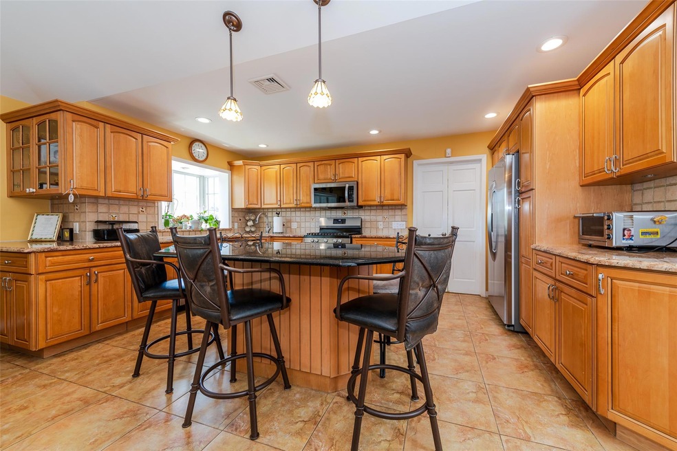 Kitchen with decorative backsplash, glass insert cabinets, a kitchen breakfast bar, recessed lighting, and brown cabinets
