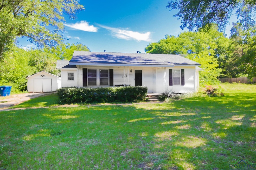 View of front of property with covered porch, an outdoor structure, a front lawn, a detached garage, and driveway