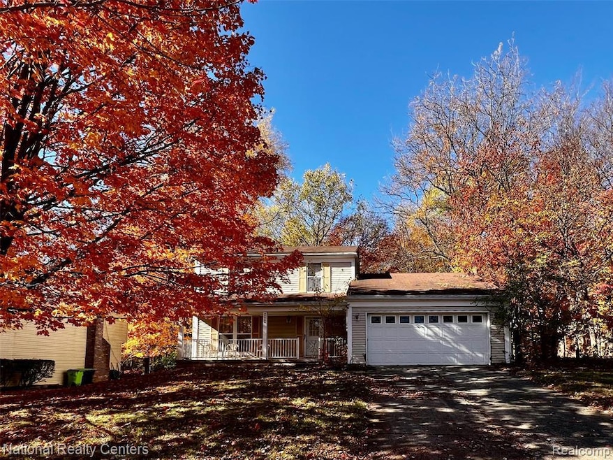 View of front facade featuring a porch, driveway, and an attached garage