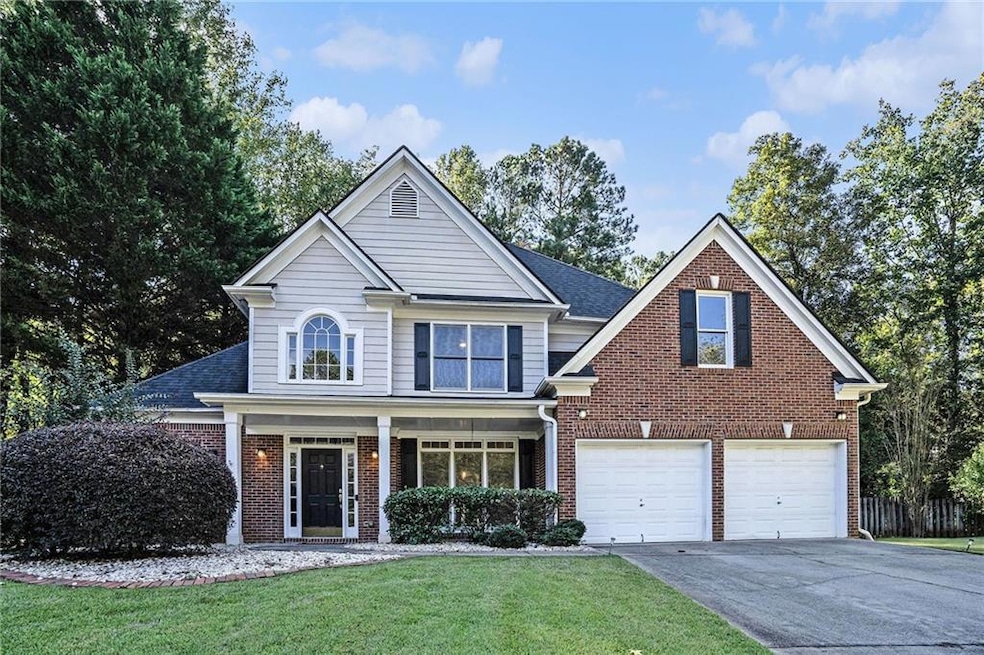 Traditional-style house featuring covered porch, brick siding, driveway, and a front lawn