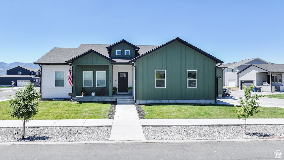 View of front of house with board and batten siding, a front lawn, and roof with shingles