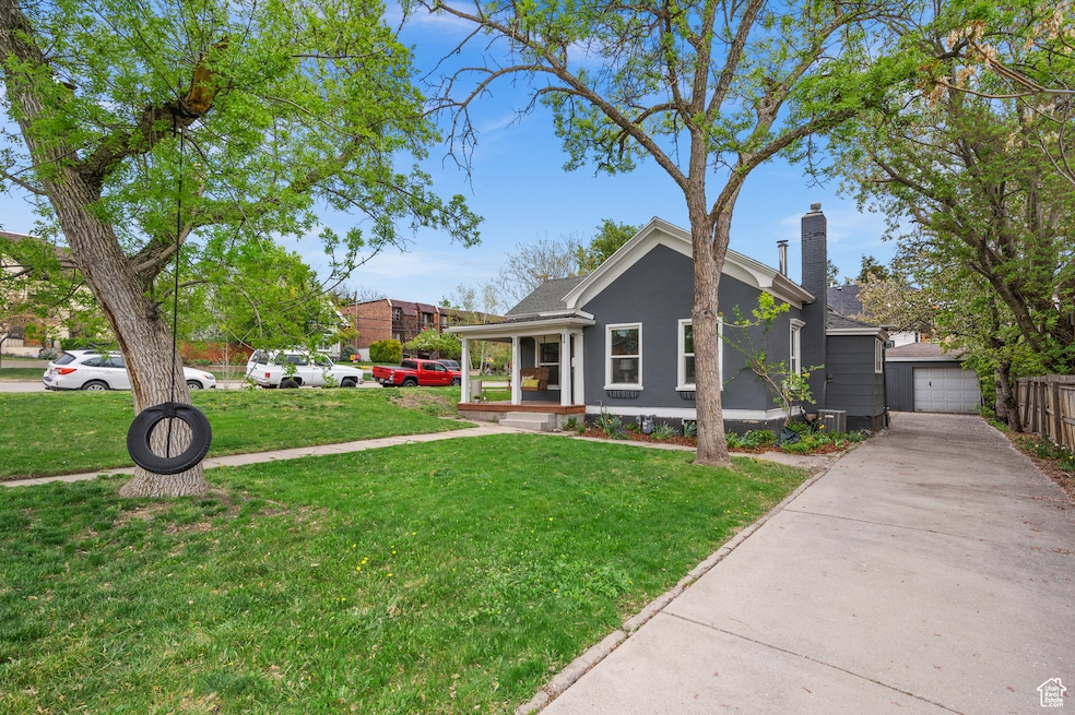 View of front of house featuring a chimney, a porch, an outdoor structure, and a front yard