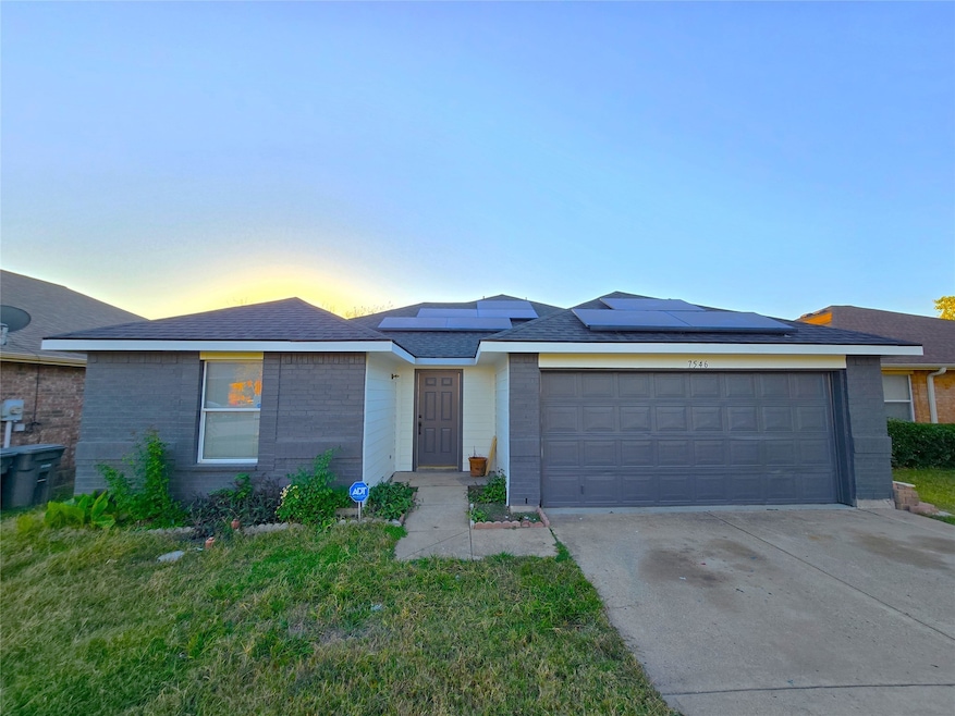 Single story home with concrete driveway, roof mounted solar panels, brick siding, and a shingled roof