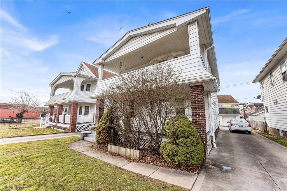 View of front of property with a garage, a front lawn, and a porch