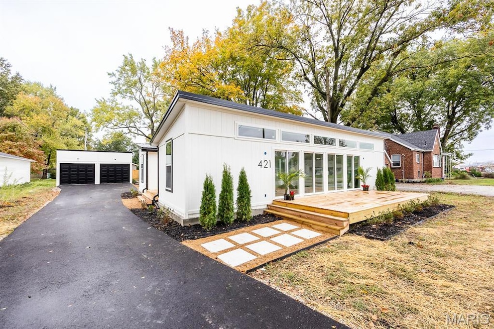Rear view of property with an outdoor structure, a wooden deck, a detached garage, and a lawn