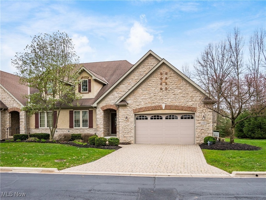 View of front of house with stone siding, a front yard, and decorative driveway