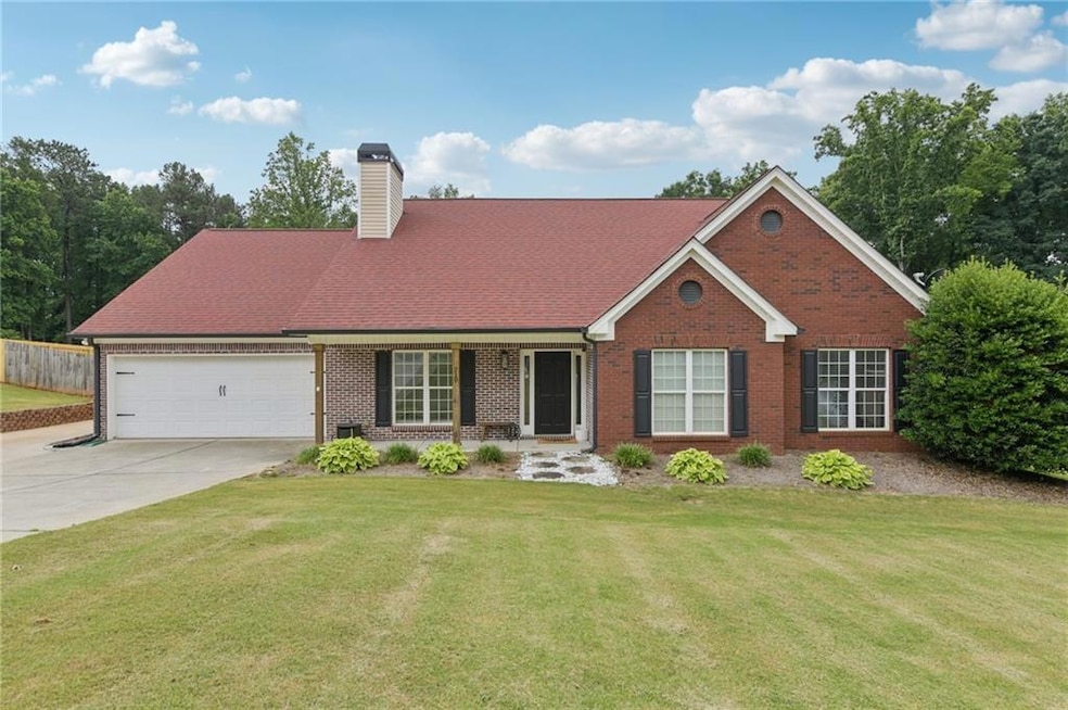 View of front facade with brick siding, driveway, an attached garage, and a chimney