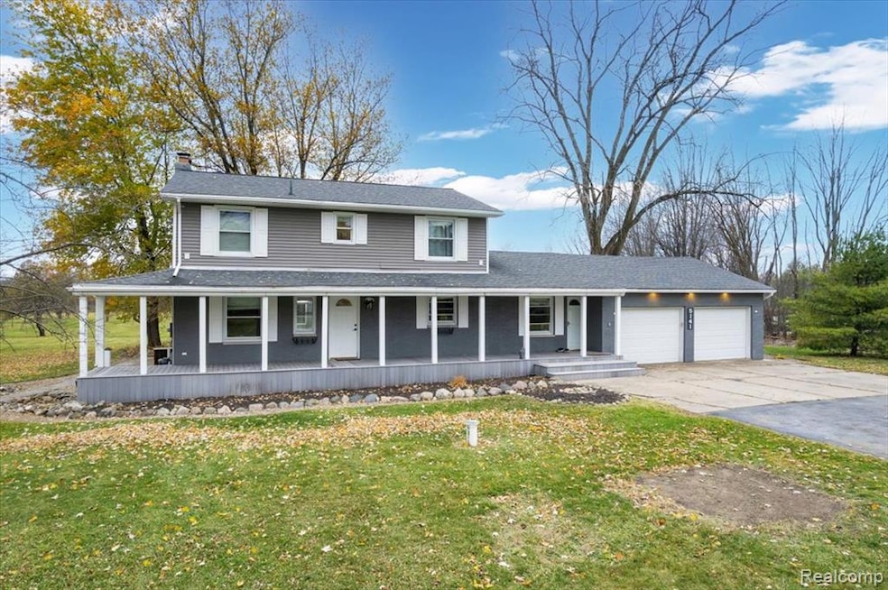 View of front of home with covered porch, a front yard, an attached garage, driveway, and roof with shingles