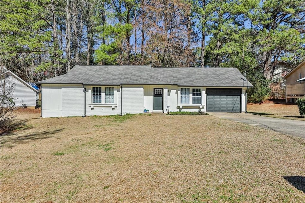 Ranch-style home with an attached garage, concrete driveway, a front lawn, and brick siding