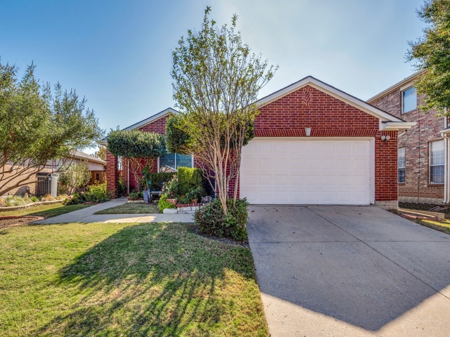 View of front of house featuring driveway, brick siding, a front lawn, and an attached garage