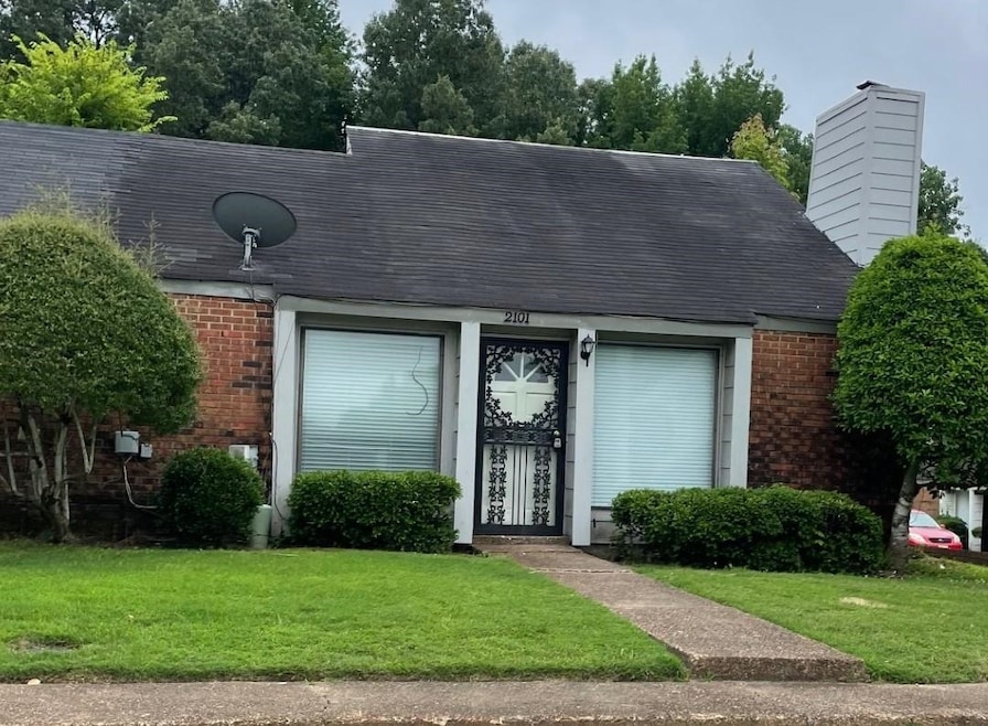 View of front facade with brick siding, a front yard, and roof with shingles