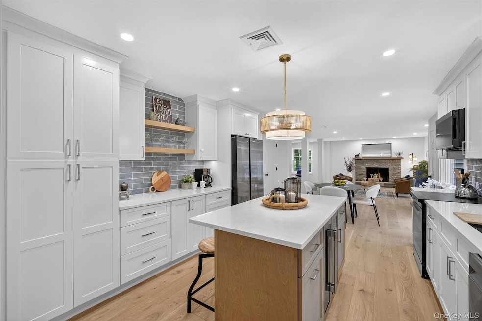 Kitchen featuring backsplash, a fireplace, light wood-type flooring, open shelves, and recessed lighting