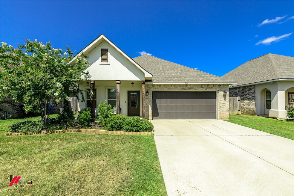 View of front facade with brick siding, roof with shingles, a front yard, a garage, and concrete driveway